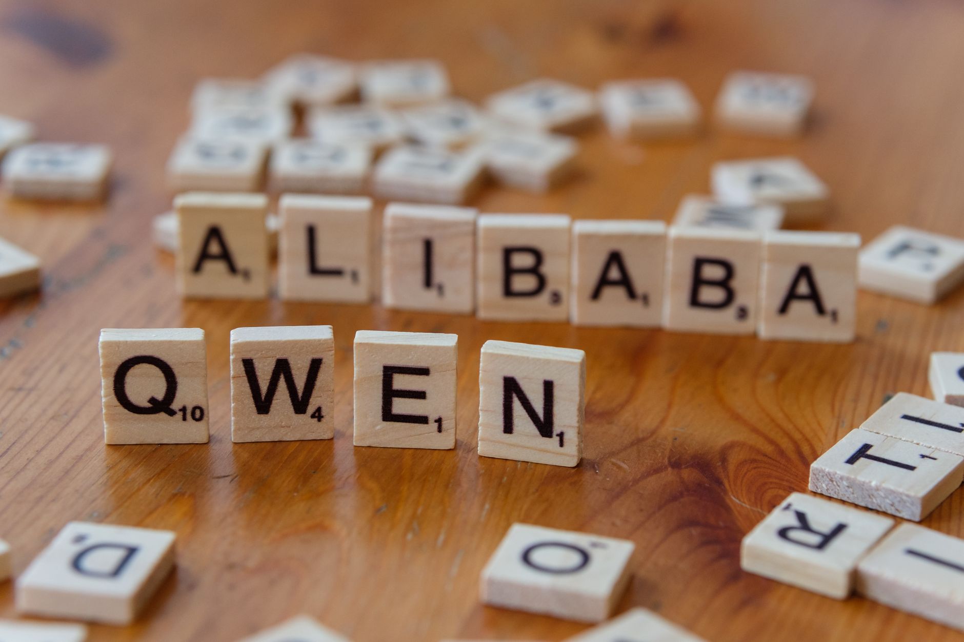 Close-up of Scrabble tiles spelling business terms on a wooden surface.